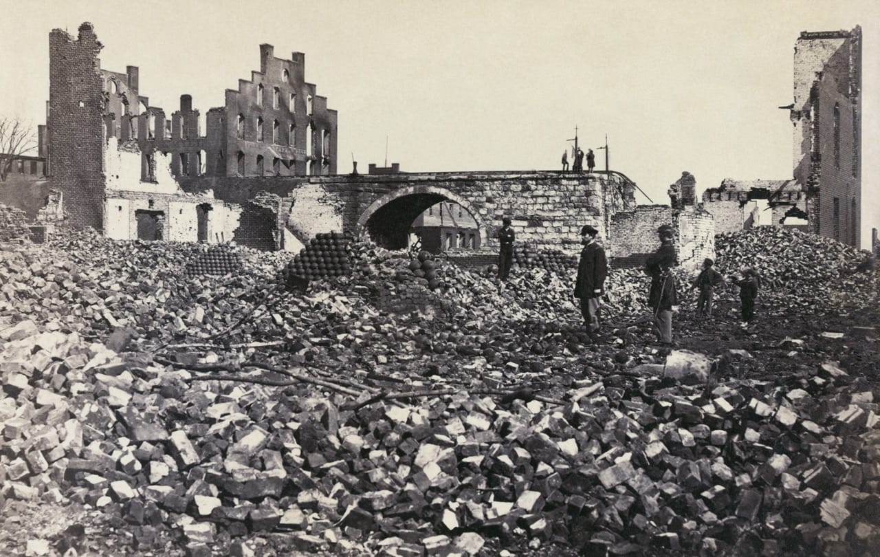 A group of people standing in a pile of rubble
Description automatically generated
